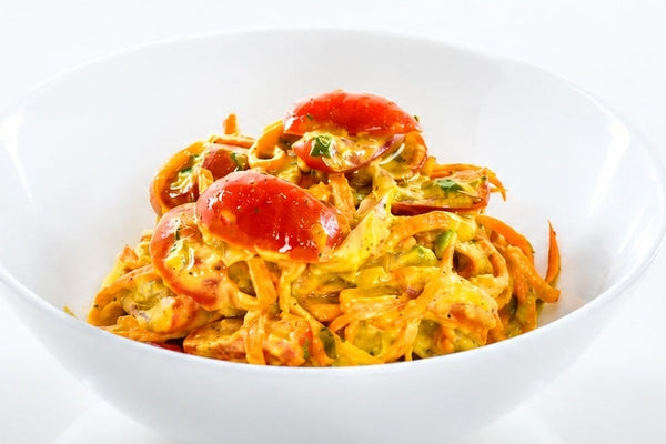 Spajuicebar carrot slaw in a white bowl .  The creamy slaw with cherry tomatoes and avocado are colorful