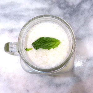 Smoothie  made with baobab with a mint leaf on top. Placedon a marble countertop 